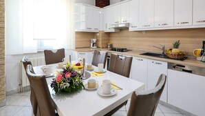 A modern kitchen with white cabinets, a wooden countertop, and a dining area with a table set for four. - Holiday Home in Policnik with Private Pool (Policnik)