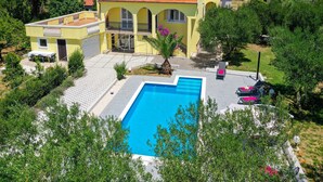 A yellow villa with a swimming pool, surrounded by greenery and a mountainous backdrop. - Holiday Home in Policnik with Private Pool (Policnik)