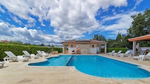 A swimming pool with lounge chairs and a building with a tiled roof. - Banjole Fun & Family Stay (Banjole)