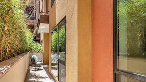 Ein schmaler, überdachter Außenbereich mit einer Bank und einer Glastür zum Balkon.