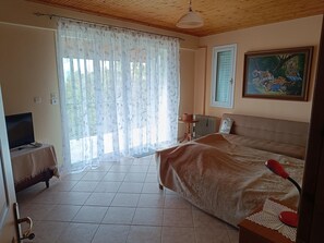 A bedroom with a bed, a television on a side table, a radiator, and a painting on the wall. - Hillview Holiday Home in Kalavrouza (Kalavrouza)