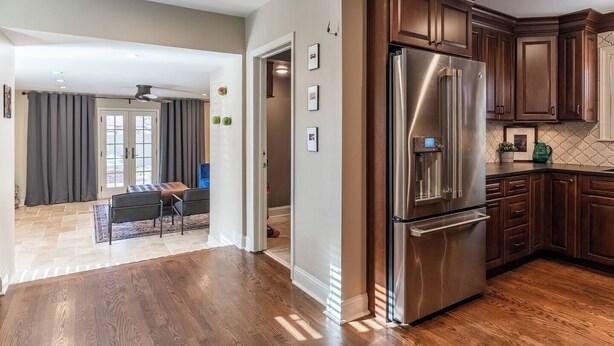 A modern kitchen with stainless steel appliances, wooden cabinets, and a herringbone floor pattern. - Gorgeous 3 Bed Ward Pkwy Home 25 (Kansas City)