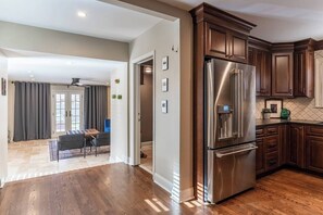Une cuisine moderne dotée d’appareils électroménagers en acier inoxydable, de meubles en bois et d’un parquet disposé en motif à chevrons.