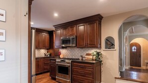 A modern kitchen with dark wood cabinets, stainless steel appliances, and a tiled backsplash. - Gorgeous 3 Bed Ward Pkwy Home 25 (Kansas City)