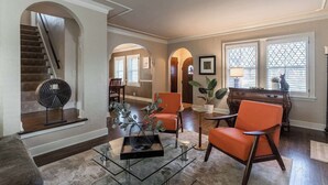 A spacious living room with a staircase, a dining area, and a view of the outside through large windows. - Gorgeous 3 Bed Ward Pkwy Home 25 (Kansas City)