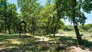 Ein Pavillon in einem bewaldeten Park mit einem See im Hintergrund.