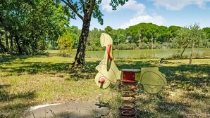 A park with a playground featuring a swing set and a seesaw.