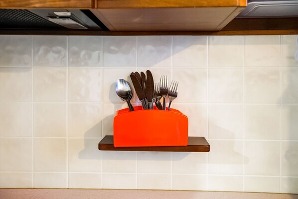 Una cocina con salpicadero de azulejos blancos, encimera de madera y un portalapaces rojo.