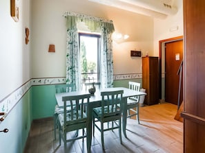 Un comedor con una mesa y sillas, una ventana con cortinas, un armario de madera y una puerta.