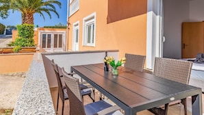 Eine Terrasse im Freien mit Esstisch, Stühlen und einer Palme.