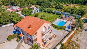 An aerial view of a residential area with a large building featuring multiple balconies, a swimming pool, and surrounding greenery. - Banjole Cozy Family Retreat (Banjole)
