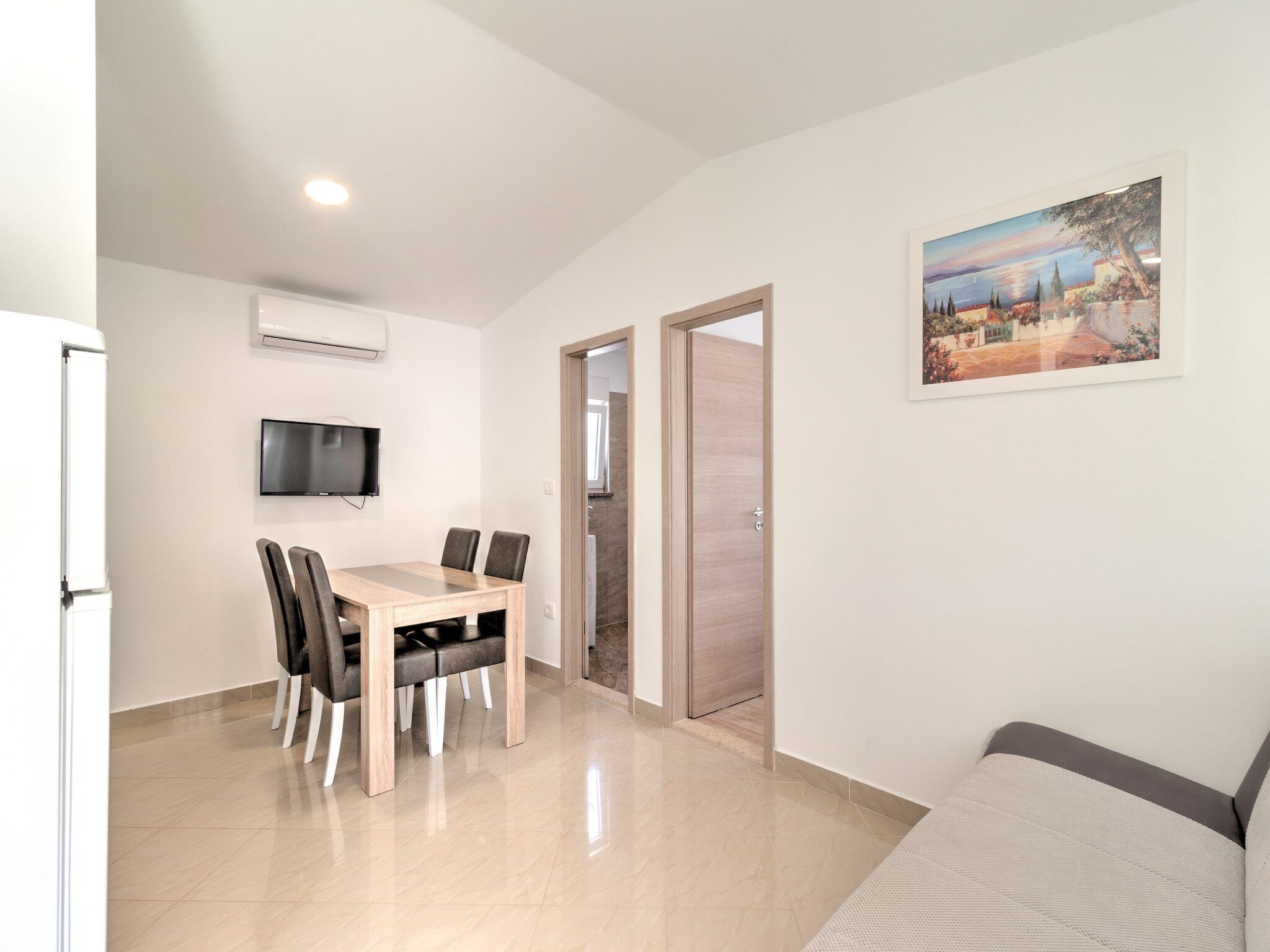Eine moderne Wohnung mit Essbereich, einem an der Wand montierten Fernseher und einem Gemälde.