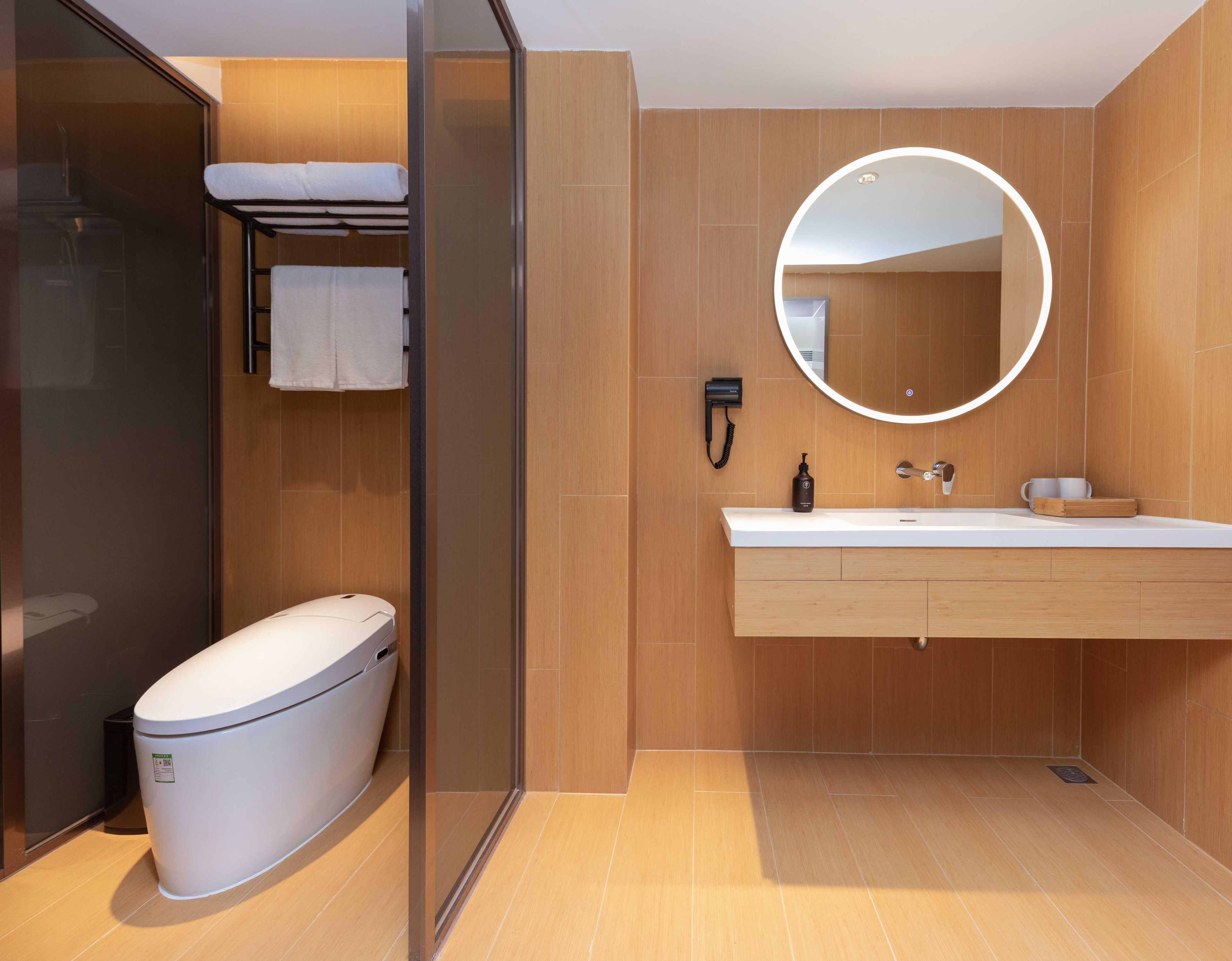 A modern bathroom with a toilet, a sink, a mirror, and a towel rack.