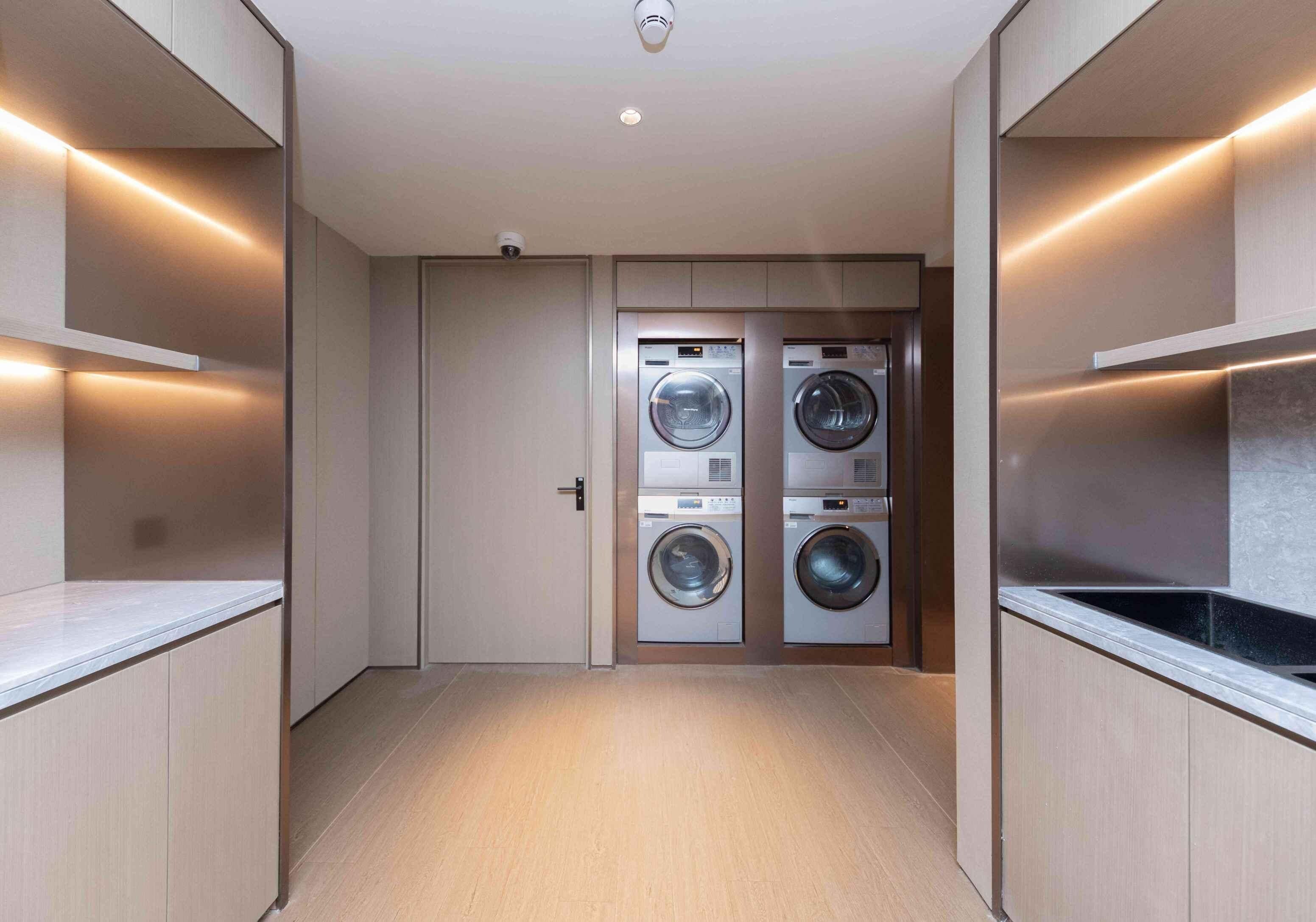 Uma lavanderia com duas máquinas de lavar, uma porta e um luminário no teto.