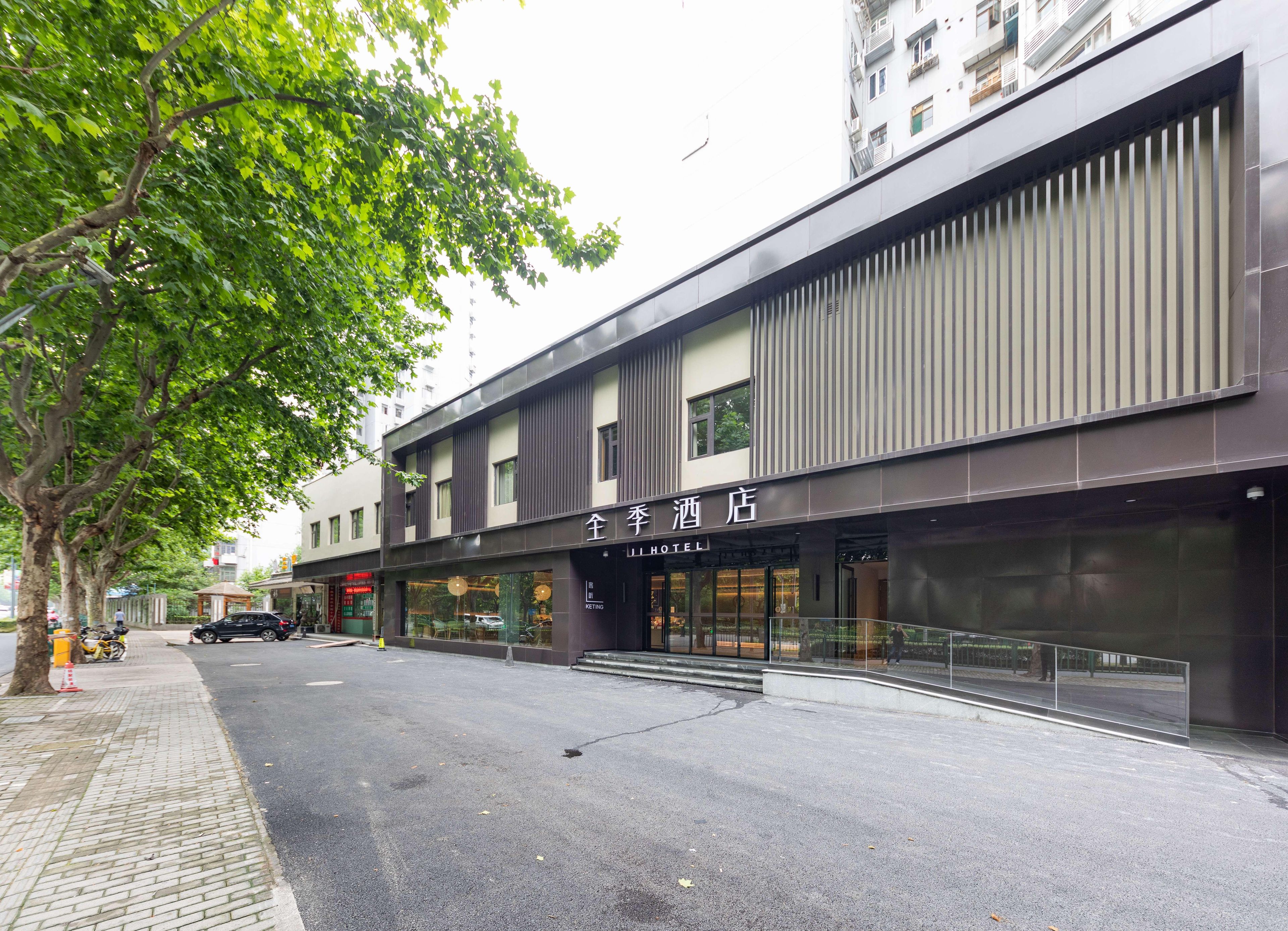 Um hotel com fachada moderna, entrada visível e rua arborizada.
