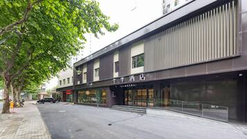 Um hotel com fachada moderna, entrada visível e rua arborizada.