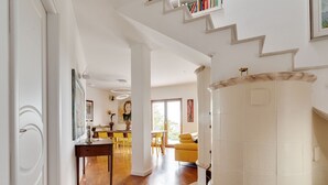 Un espacio habitable amplio con piso de madera, un sofá amarillo y una mesa de comedor con sillas.