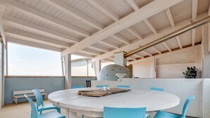 Una mesa redonda con sillas azules en una habitación con techo alto y vigas a la vista.
