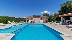 A swimming pool with lounge chairs, a children's slide, and a building with a tiled roof. - Mobile Home in Banjole near Beach Centinera (Banjole)