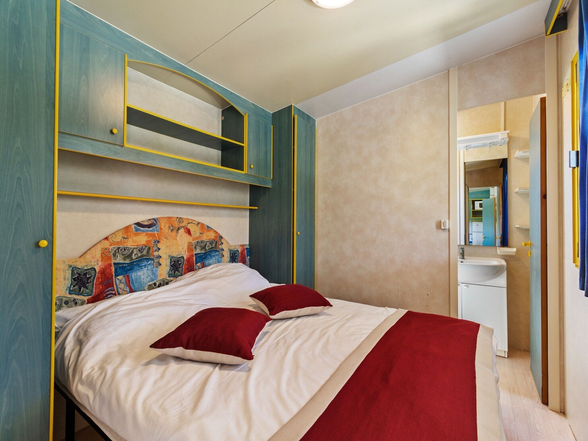 A bedroom with a bed, a bedside table, and a mirror.