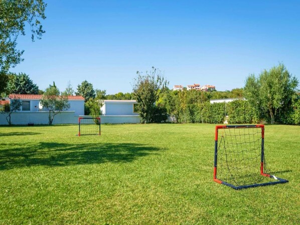 A grassy field with two soccer goals and a white building in the background. - Banjole Apartment near Beach (Banjole)