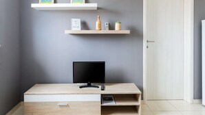 Une pièce moderne équipée d’un bureau, de deux étagères fixées au mur, d’une porte et d’un tableau encadré accroché au mur.