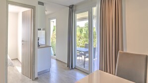 A modern hotel room with a dining area, a kitchen, and a balcony with a table and chairs. - Mobile Home in Banjole near Beach & Pool (Banjole)