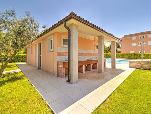 Un bâtiment d’un seul étage doté d’une terrasse carrelée et d’une piscine.
