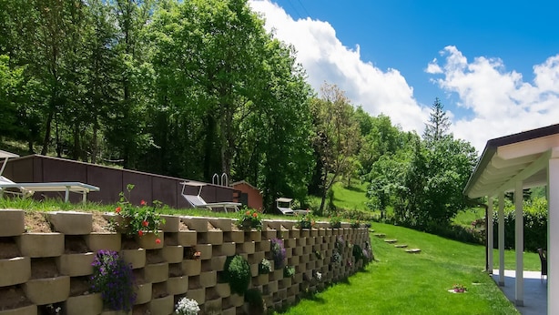 Un giardino con un muro in mattoni, arredi da esterno e una zona coperta.
