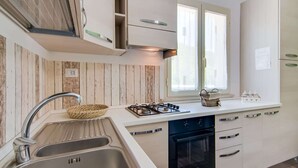 Una cucina moderna con lavello in acciaio inossidabile, piano cottura a gas e mobili bianchi.