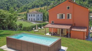 Una casa a due piani con una piscina in primo piano e montagne sullo sfondo.