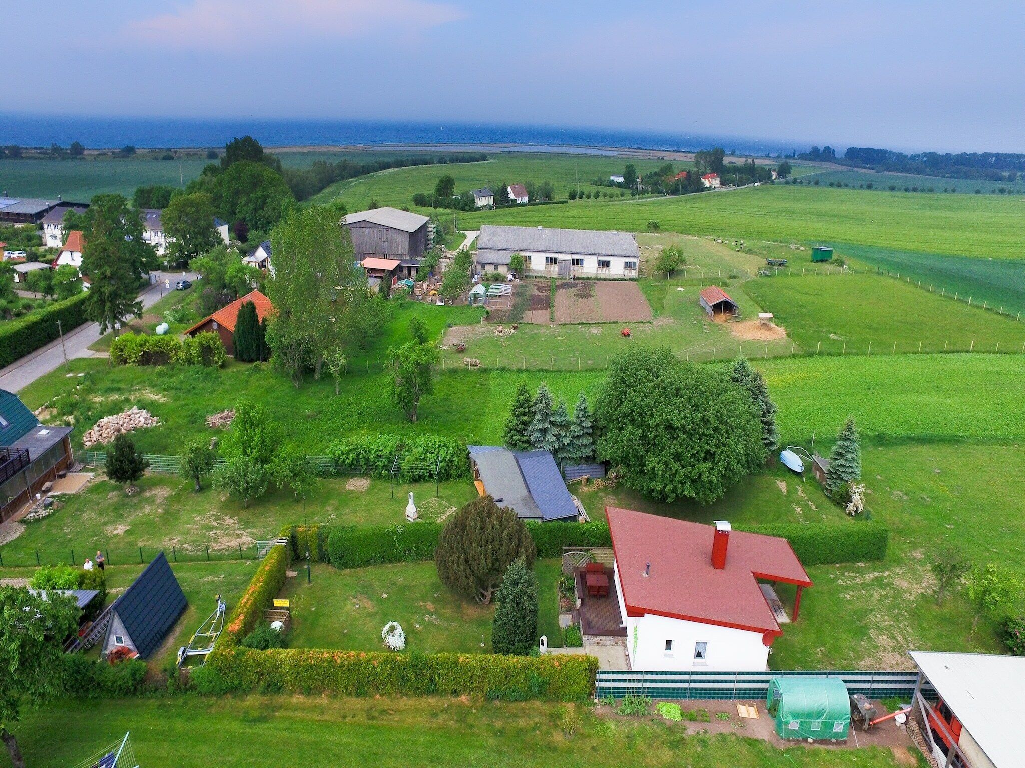A rural landscape with houses, green fields, and a body of water in the distance.
