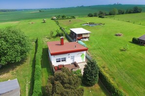 Uma casa com telhado vermelho, paredes brancas e um jardim.