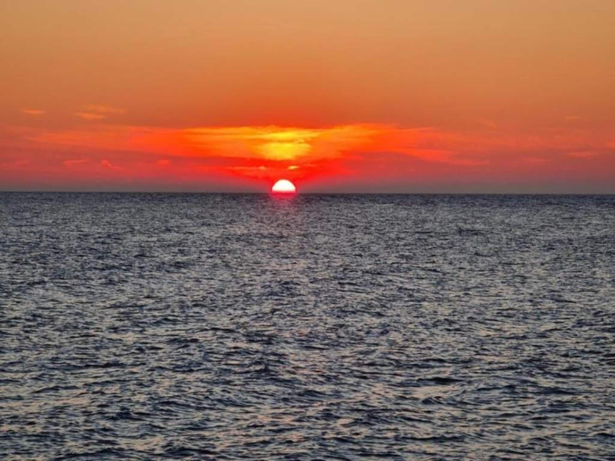 A sunset over the ocean with calm waters.