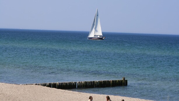 A sailboat on calm waters with a sandy beach in the foreground. - Cozy Baltic Escape for 2 Guests (Bastorf / Kägsdorf)