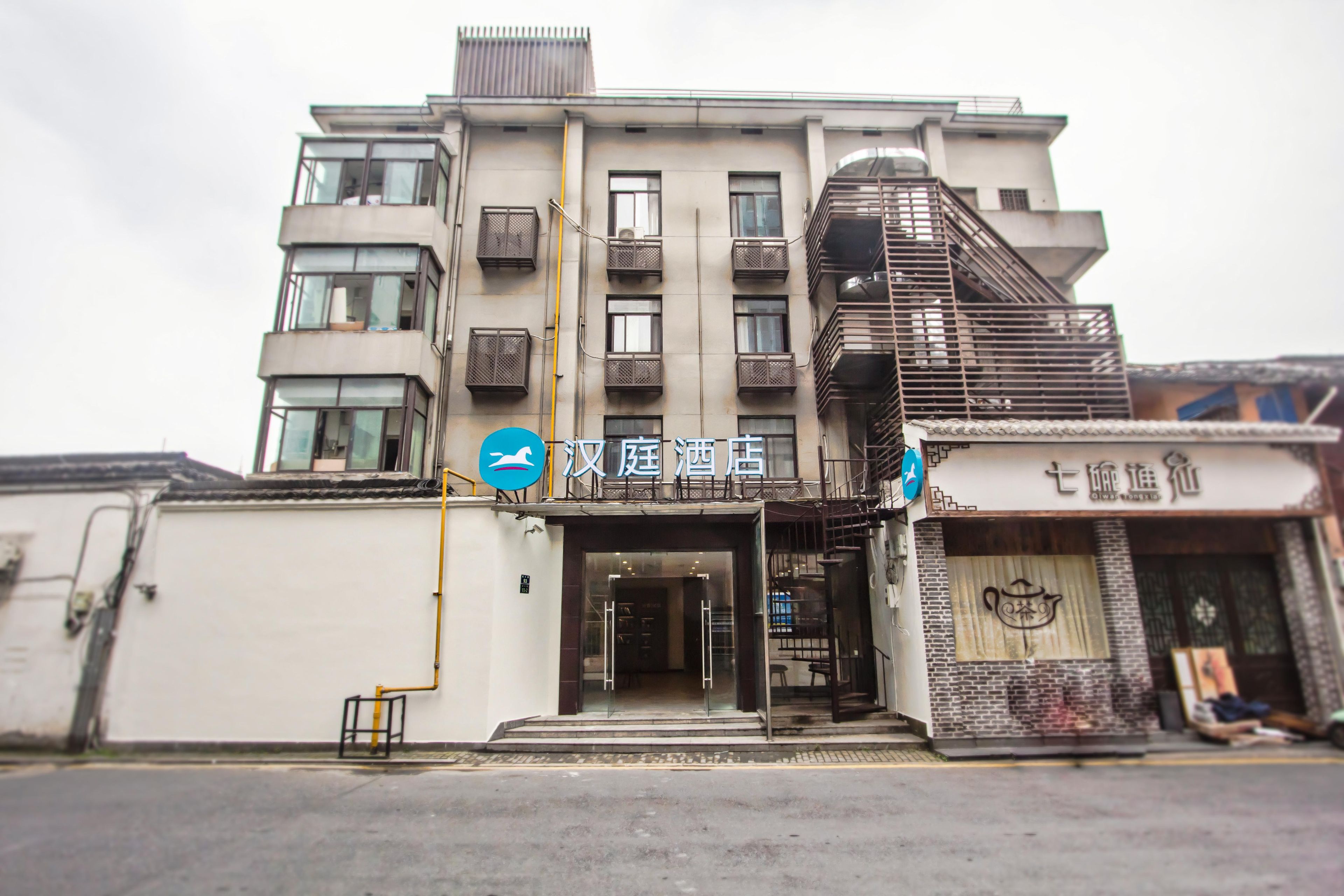 A multi-story hotel with a modern facade, a visible entrance, and a staircase leading to the upper floors.