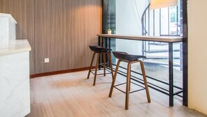A modern kitchen with wooden paneling, a white countertop, and two bar stools.