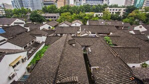 A traditional building with multiple roofs and a modern skyscraper in the background.