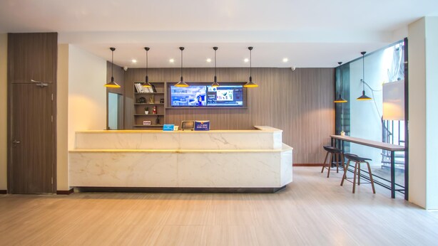 A modern reception area with a marble counter, pendant lighting, a flat-screen TV, and a seating area with bar stools.