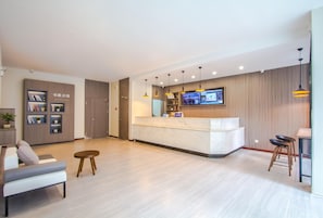 Un moderno vestíbulo de hotel con mostrador de recepción, zona de estar y televisión montada en la pared.