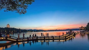 Una escena tranquila junto al lago con un pagode tradicional y un puente de madera.