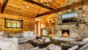 L’intérieur chaleureux d’un chalet en bois, avec une cheminée en pierre, des murs en bois et un coin salon confortable.