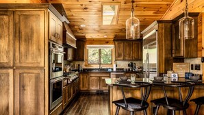 L’intérieur d’un chalet en bois comprend une cuisine dotée d’un îlot central, de tabourets de bar et d’une enseigne accueillante.