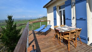 Une terrasse en bois avec une table et des chaises, offrant une vue sur un paysage magnifique.