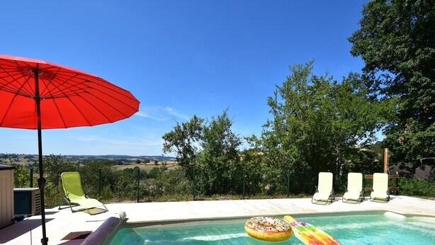 Une piscine avec des chaises longues et un parasol.