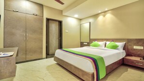 A hotel room with a bed, a desk, a wardrobe, and a ceiling fan. - Treebo Sriz Cozy Seethamadhara (Visakhapatnam)