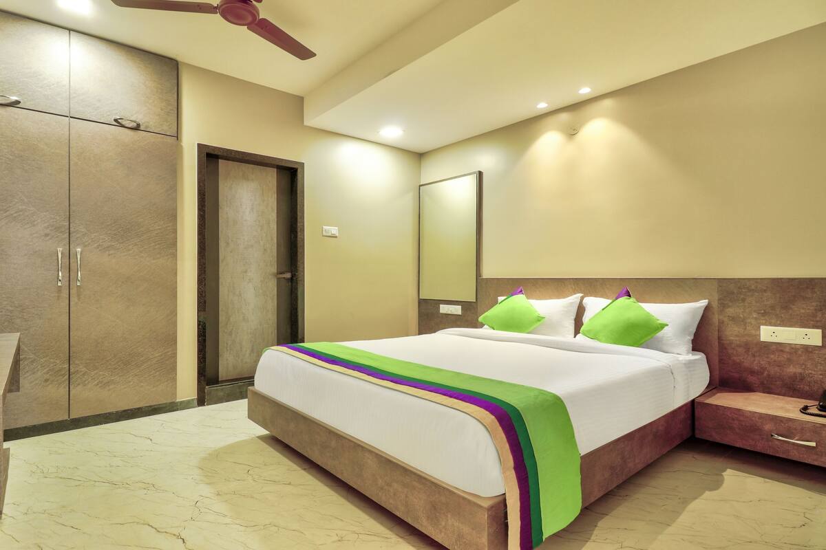 Ein Hotelzimmer mit Bett, Schreibtisch, Kleiderschrank und Deckenventilator.