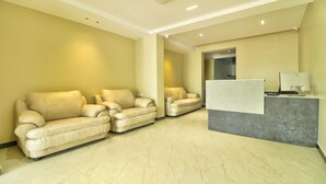A modern reception area with a marble floor, beige sofas, and a desk with a computer. - Treebo Sriz Cozy Seethamadhara (Visakhapatnam)