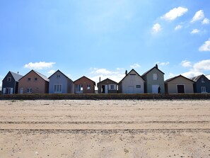 A row of beach houses with a sandy beach in front.