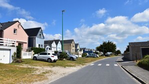 A residential street with houses, parked cars, and a clear sky. - Beautiful holiday home with courtyard (Ravenoville-Plage)
